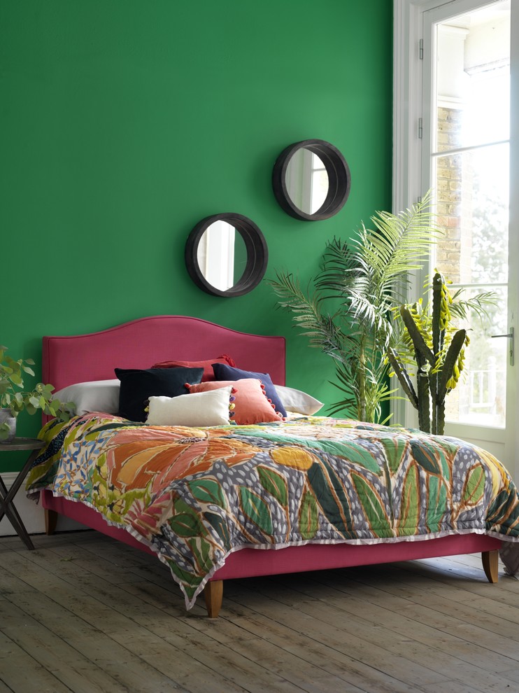 Example of a mid-sized island style guest medium tone wood floor bedroom design in London with green walls