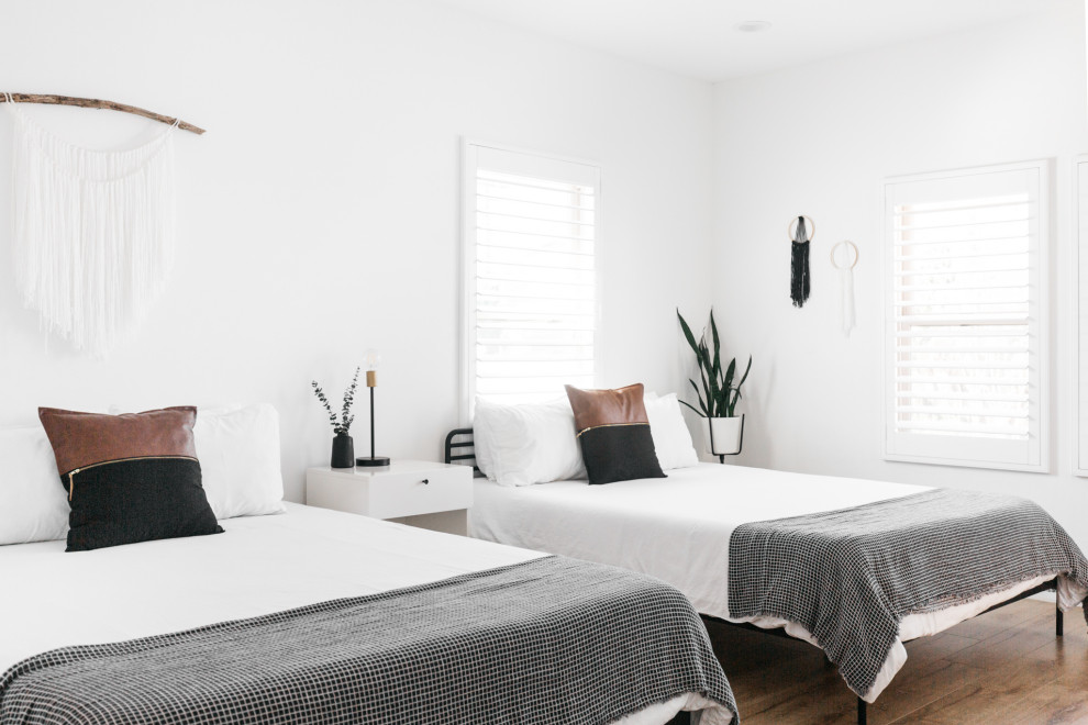 Diseño de dormitorio actual con paredes blancas, suelo de madera en tonos medios y suelo marrón