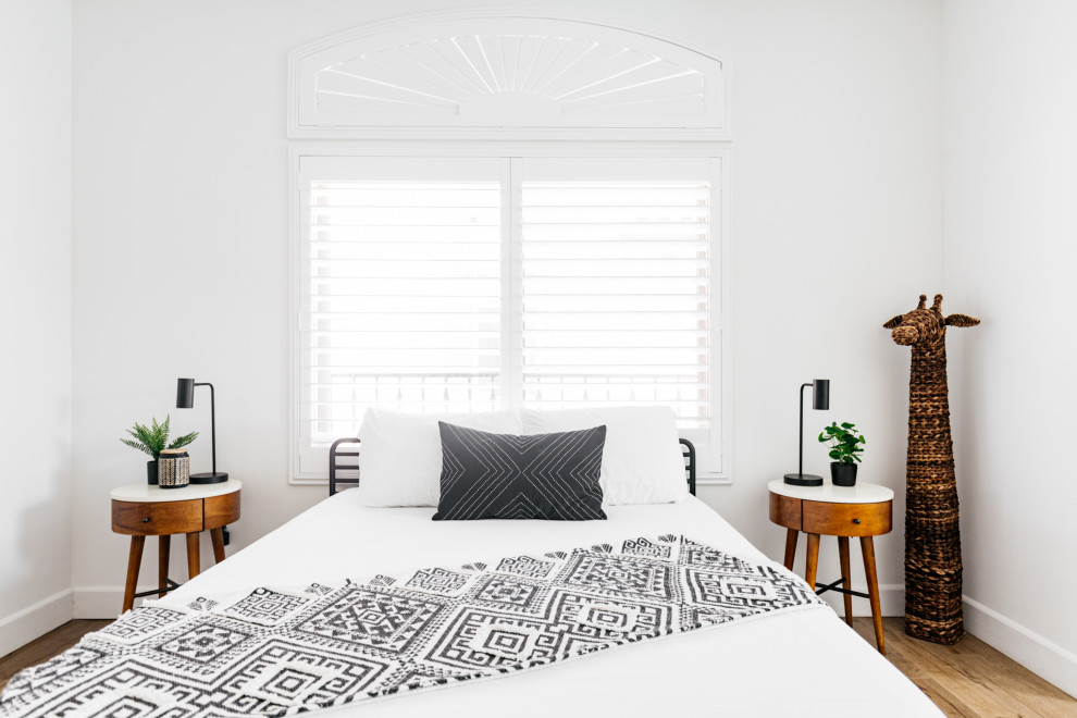 Trendy medium tone wood floor and brown floor bedroom photo in Los Angeles with white walls