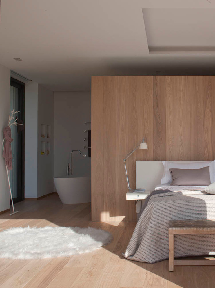 Ejemplo de dormitorio principal contemporáneo sin chimenea con paredes blancas y suelo de madera clara