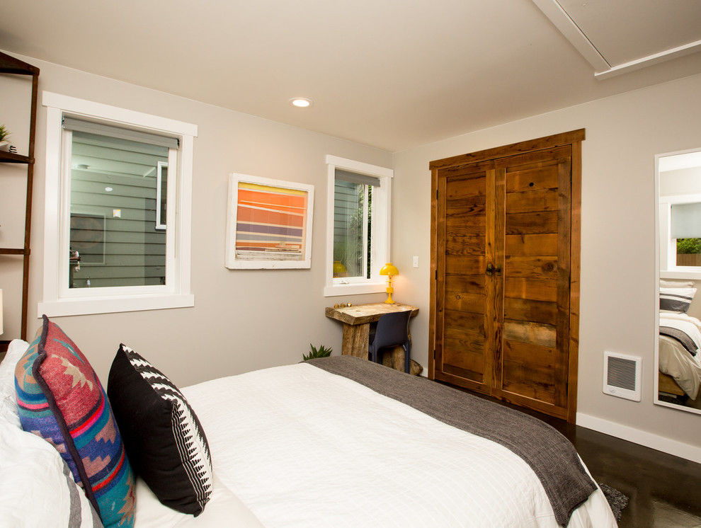 Imagen de dormitorio principal rústico de tamaño medio sin chimenea con paredes grises, suelo de cemento y suelo marrón