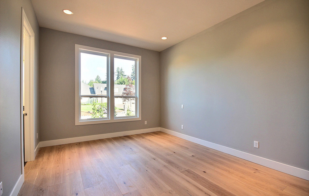 Cette image montre une grande chambre d'amis minimaliste avec un mur gris, parquet clair, aucune cheminée et un sol marron.