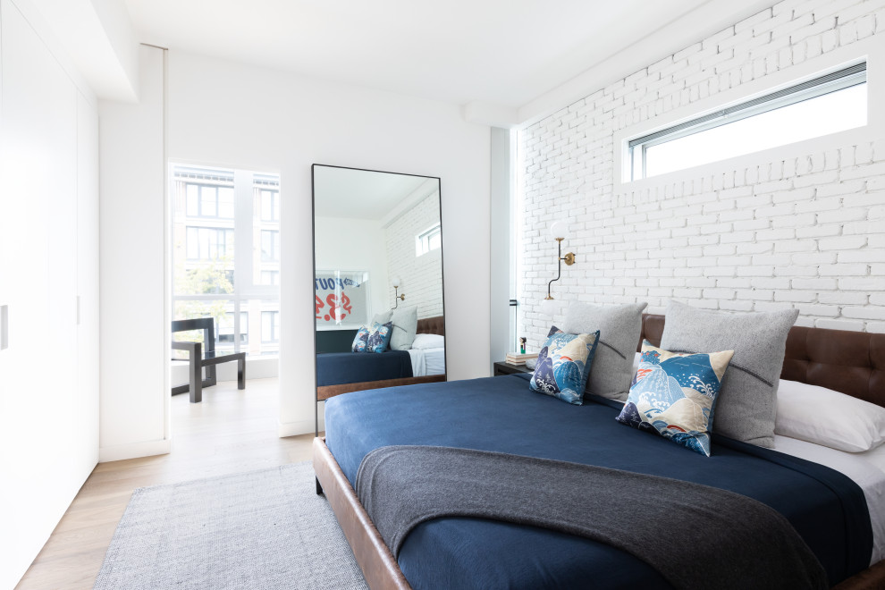 Modernes Schlafzimmer mit weißer Wandfarbe, braunem Holzboden, braunem Boden und Ziegelwänden in Sonstige