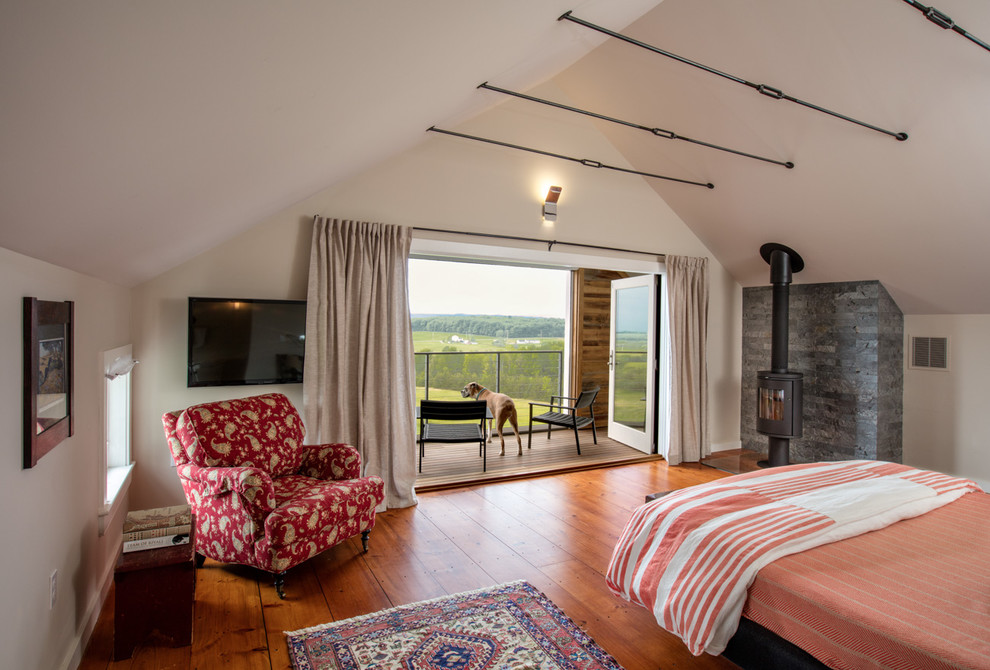 Großes Country Hauptschlafzimmer mit beiger Wandfarbe, braunem Holzboden, Kaminofen und Kaminumrandung aus Stein in Burlington