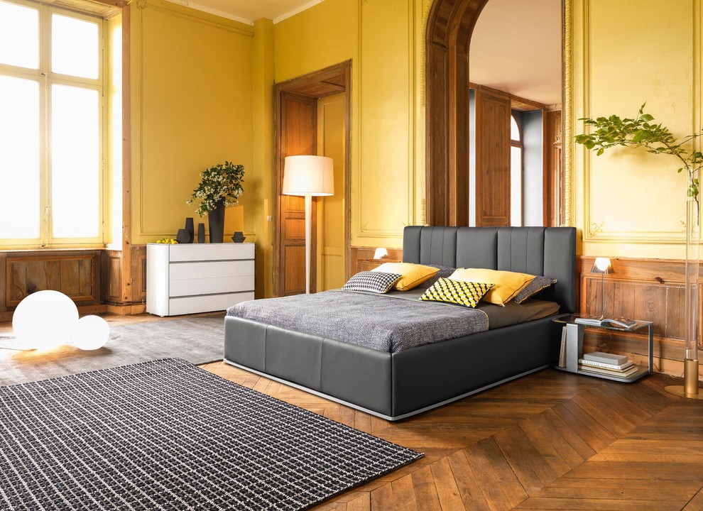 Modelo de dormitorio principal bohemio de tamaño medio sin chimenea con paredes amarillas y suelo de madera en tonos medios