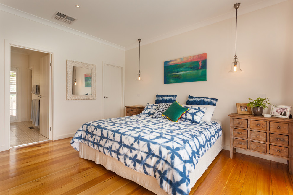 Ejemplo de habitación de invitados costera de tamaño medio con paredes blancas, suelo de madera en tonos medios y suelo marrón