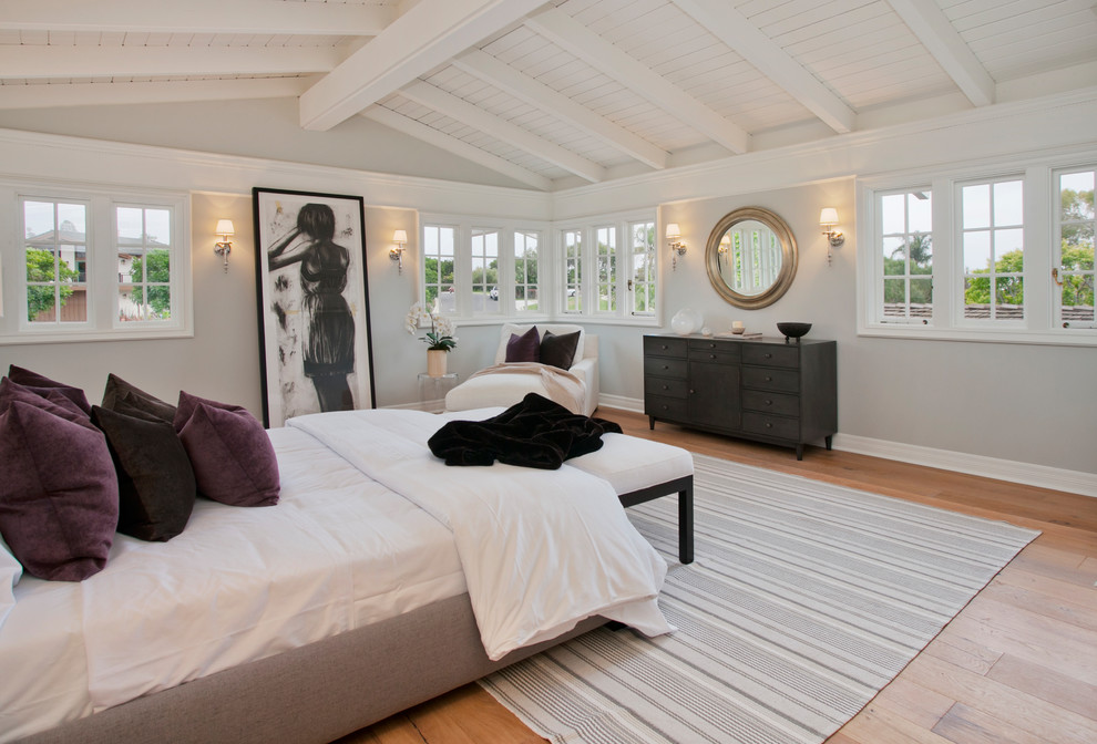 ロサンゼルスにある広いトランジショナルスタイルのおしゃれな主寝室 (グレーの壁、淡色無垢フローリング、標準型暖炉、木材の暖炉まわり) のインテリア