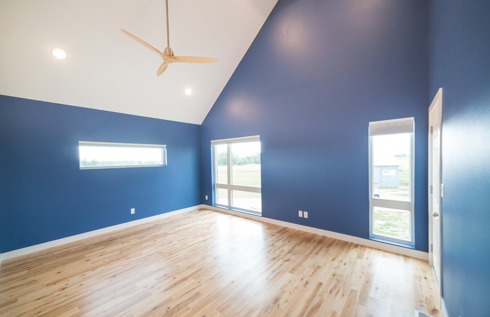 Großes Country Hauptschlafzimmer ohne Kamin mit blauer Wandfarbe, hellem Holzboden und braunem Boden in Sonstige