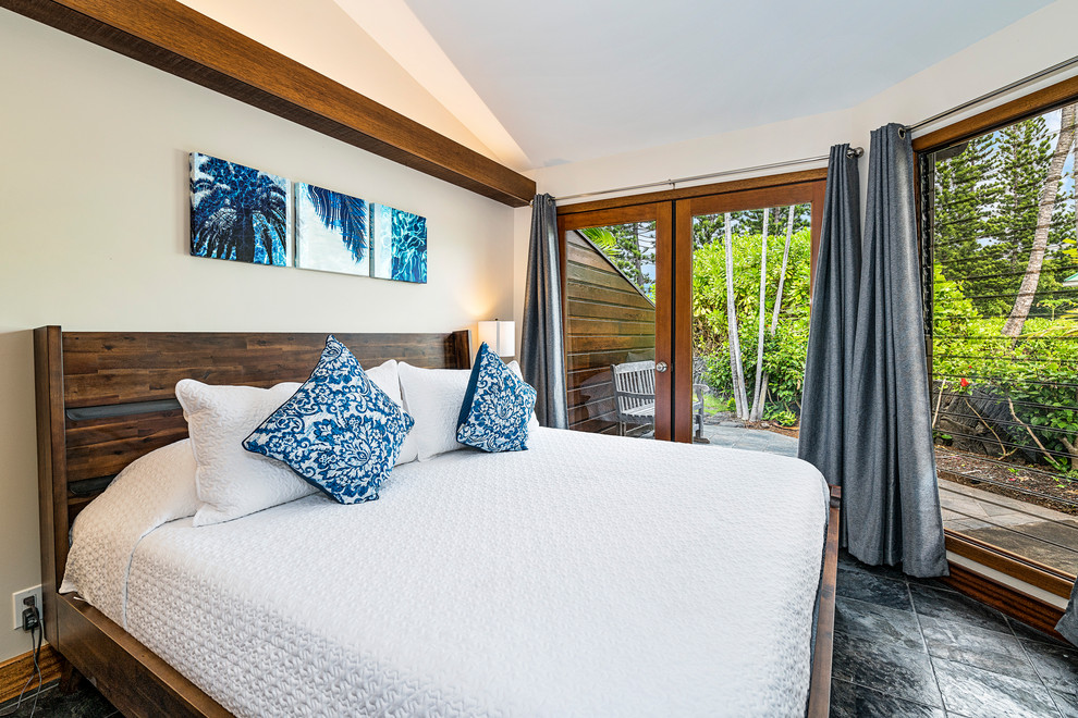Example of a mid-sized island style guest slate floor and black floor bedroom design in Hawaii with white walls