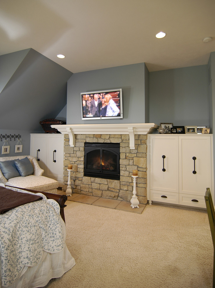 На фото: хозяйская спальня в стиле кантри с синими стенами, ковровым покрытием, бежевым полом, стандартным камином и фасадом камина из камня