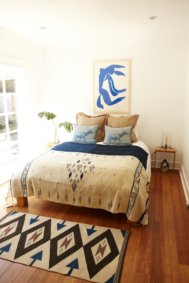 Foto di una camera da letto boho chic con pareti bianche e pavimento in legno massello medio