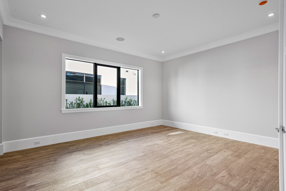 Idée de décoration pour une chambre d'amis design avec un mur gris, parquet clair et un sol marron.