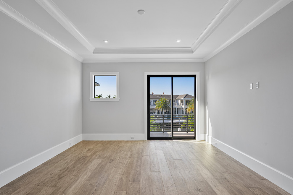 Modernes Hauptschlafzimmer mit grauer Wandfarbe, hellem Holzboden und braunem Boden in Miami
