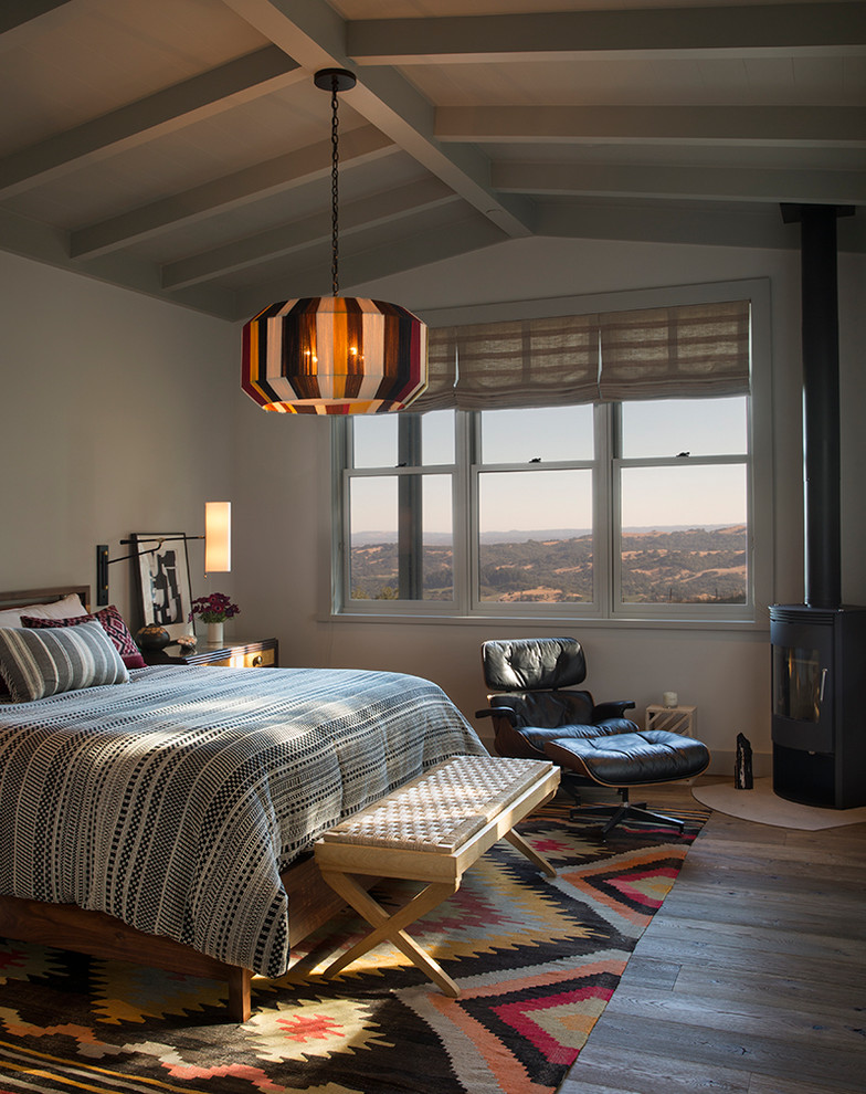 Landhaus Schlafzimmer mit weißer Wandfarbe, braunem Holzboden, Kaminofen und braunem Boden in San Francisco