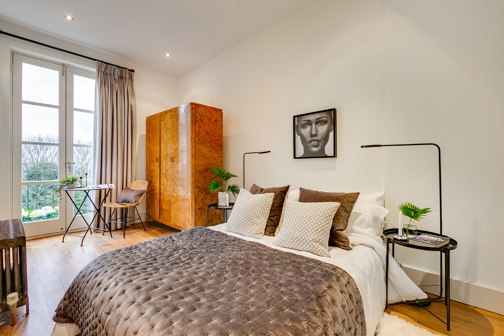 Modern master bedroom in London with white walls, light hardwood flooring and beige floors.