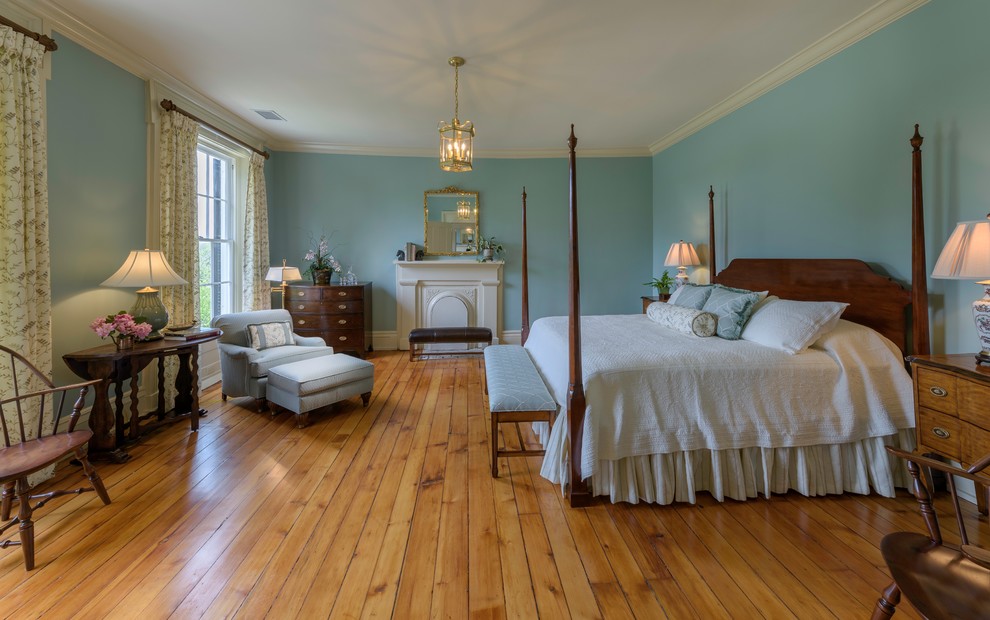 Idées déco pour une grande chambre parentale classique avec un mur bleu, un sol en bois brun, une cheminée standard, un manteau de cheminée en bois et un sol marron.