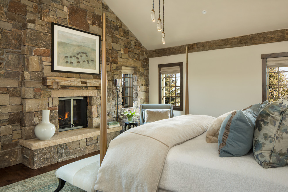Exemple d'une chambre parentale montagne avec parquet foncé, un poêle à bois, un manteau de cheminée en pierre et un mur beige.