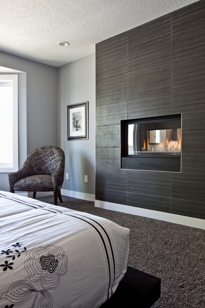 Modelo de habitación de invitados actual de tamaño medio con paredes grises, moqueta, chimenea de doble cara y marco de chimenea de baldosas y/o azulejos