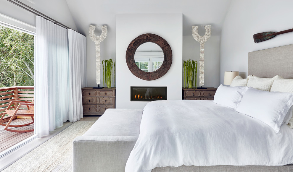 Стильный дизайн: большая хозяйская спальня в современном стиле с белыми стенами, светлым паркетным полом, стандартным камином и фасадом камина из штукатурки - последний тренд