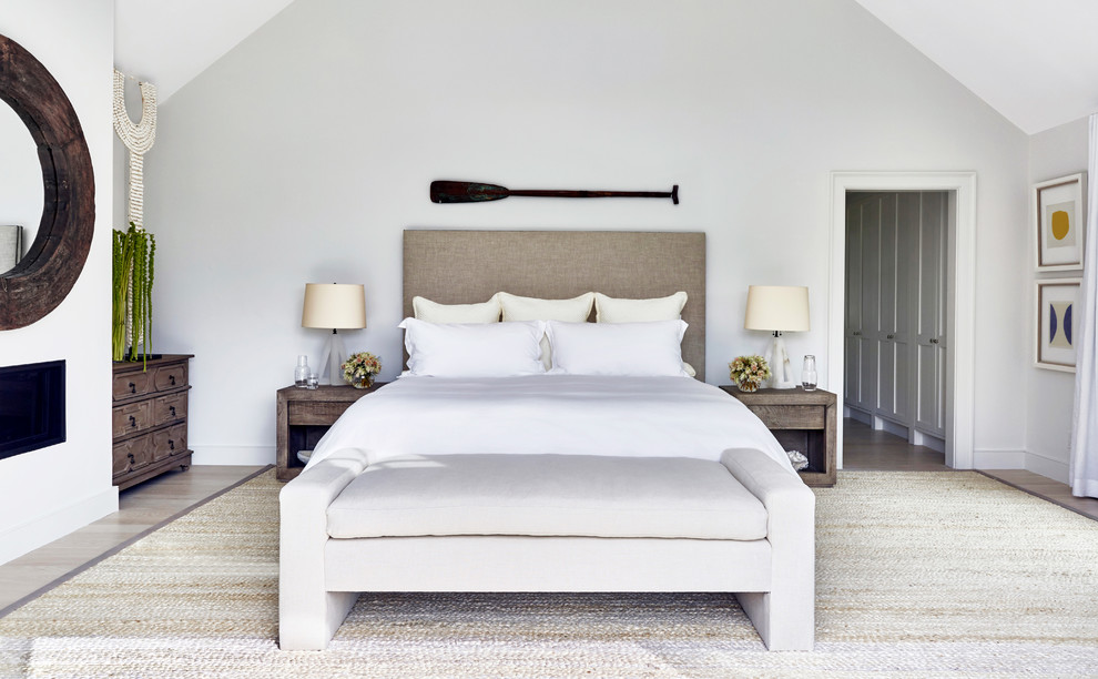 Пример оригинального дизайна: большая хозяйская спальня в современном стиле с белыми стенами, светлым паркетным полом, стандартным камином и фасадом камина из штукатурки