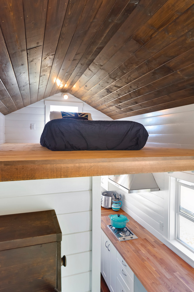 Bild på ett litet maritimt sovloft, med vita väggar och plywoodgolv