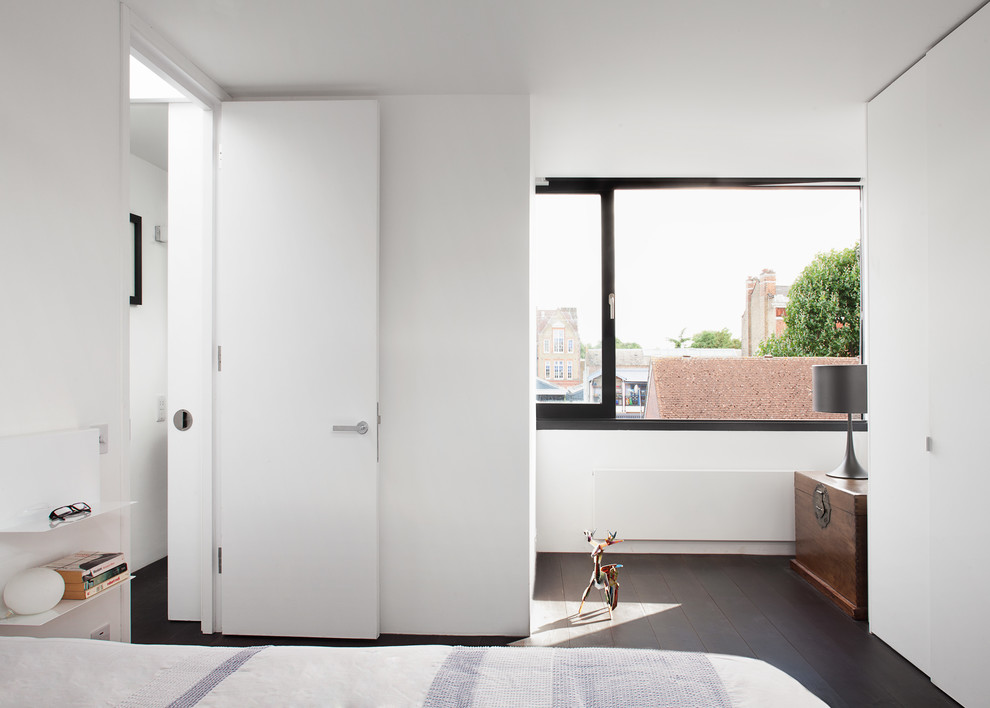 Mittelgroßes Modernes Hauptschlafzimmer ohne Kamin mit weißer Wandfarbe und dunklem Holzboden in London