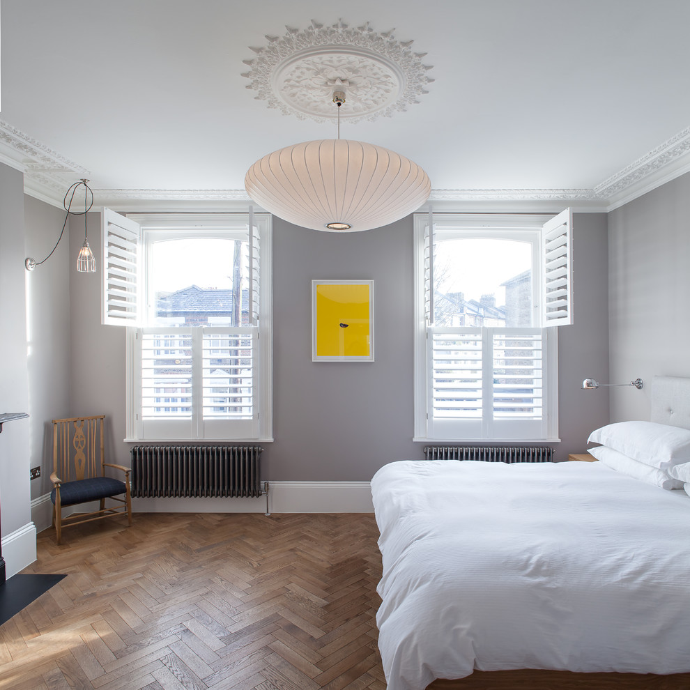 Mittelgroßes Modernes Hauptschlafzimmer mit grauer Wandfarbe, dunklem Holzboden, Kamin, Kaminumrandung aus Metall und braunem Boden in London