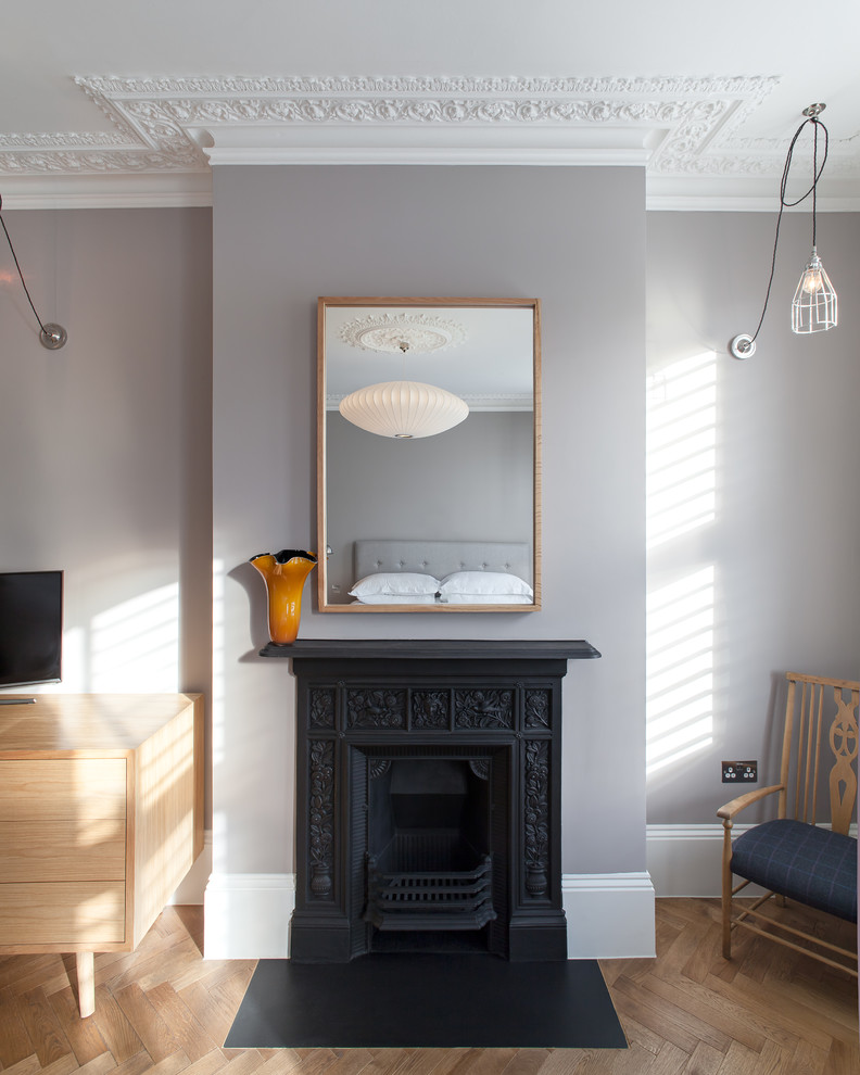 ロンドンにある中くらいなコンテンポラリースタイルのおしゃれな主寝室 (グレーの壁、濃色無垢フローリング、標準型暖炉、金属の暖炉まわり、茶色い床)