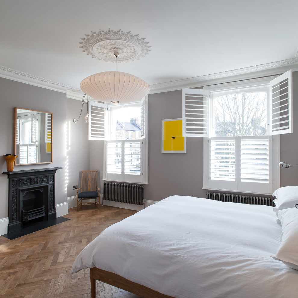 ロンドンにある中くらいなコンテンポラリースタイルのおしゃれな主寝室 (グレーの壁、無垢フローリング、標準型暖炉、金属の暖炉まわり)