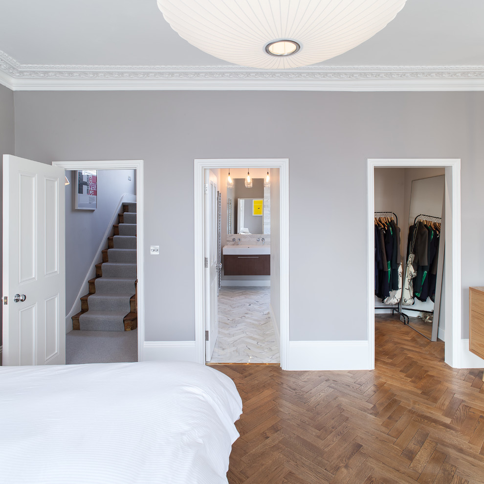 Idée de décoration pour une chambre parentale design de taille moyenne avec un mur gris et un sol en bois brun.