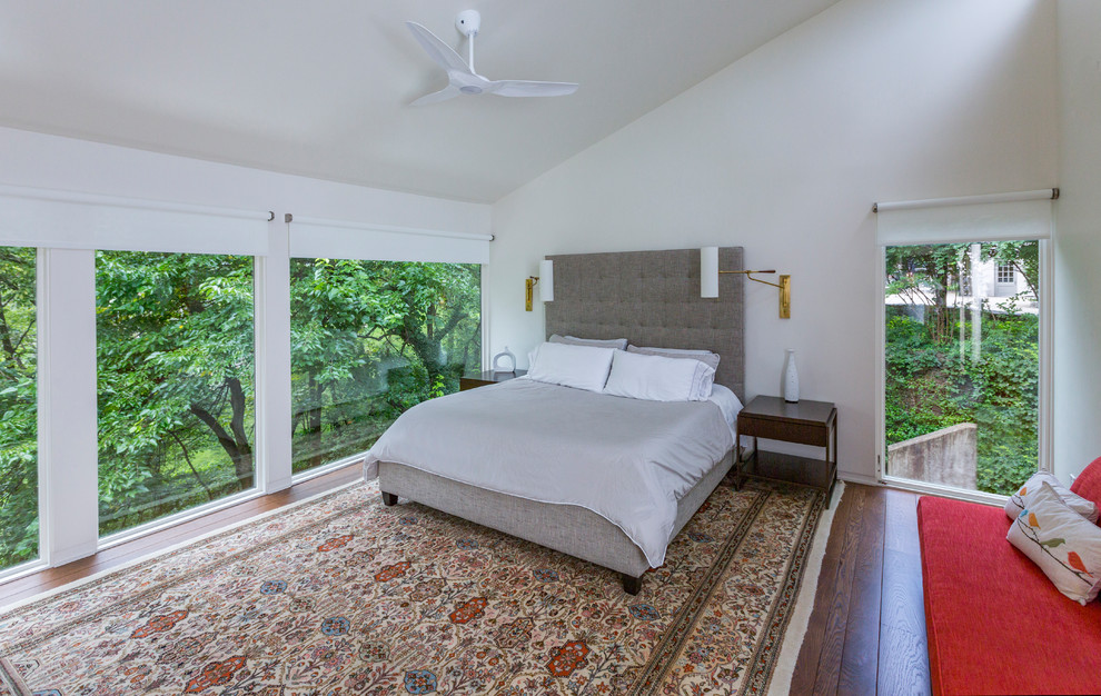 Modelo de dormitorio principal minimalista de tamaño medio con paredes blancas, suelo de madera en tonos medios y suelo marrón