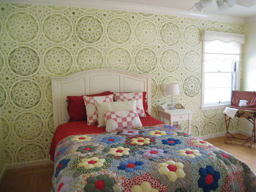 This is an example of a country guest bedroom in San Francisco with green walls and light hardwood flooring.