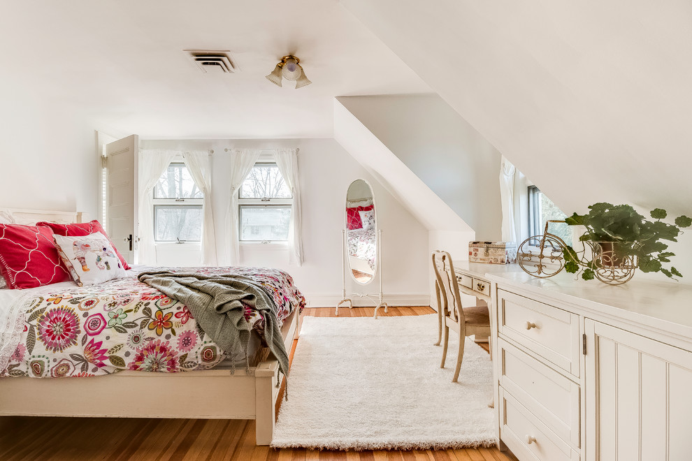 This is an example of a large traditional guest loft bedroom in New York with white walls and medium hardwood flooring.