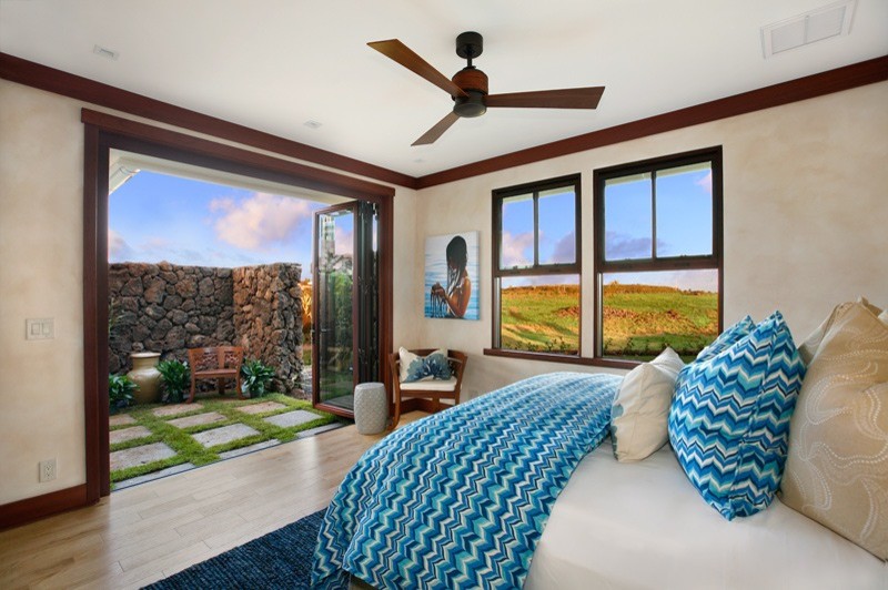 ハワイにある広いトロピカルスタイルのおしゃれな客用寝室 (ベージュの壁、淡色無垢フローリング) のインテリア