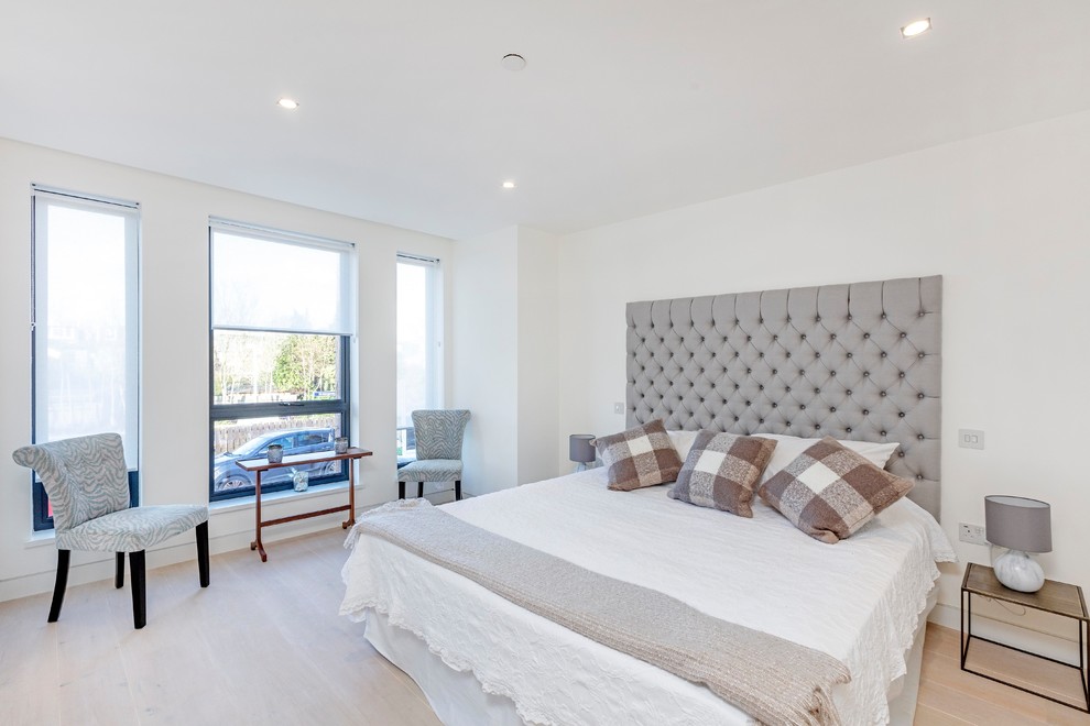 Inspiration for a contemporary bedroom in London with white walls, light hardwood flooring and beige floors.