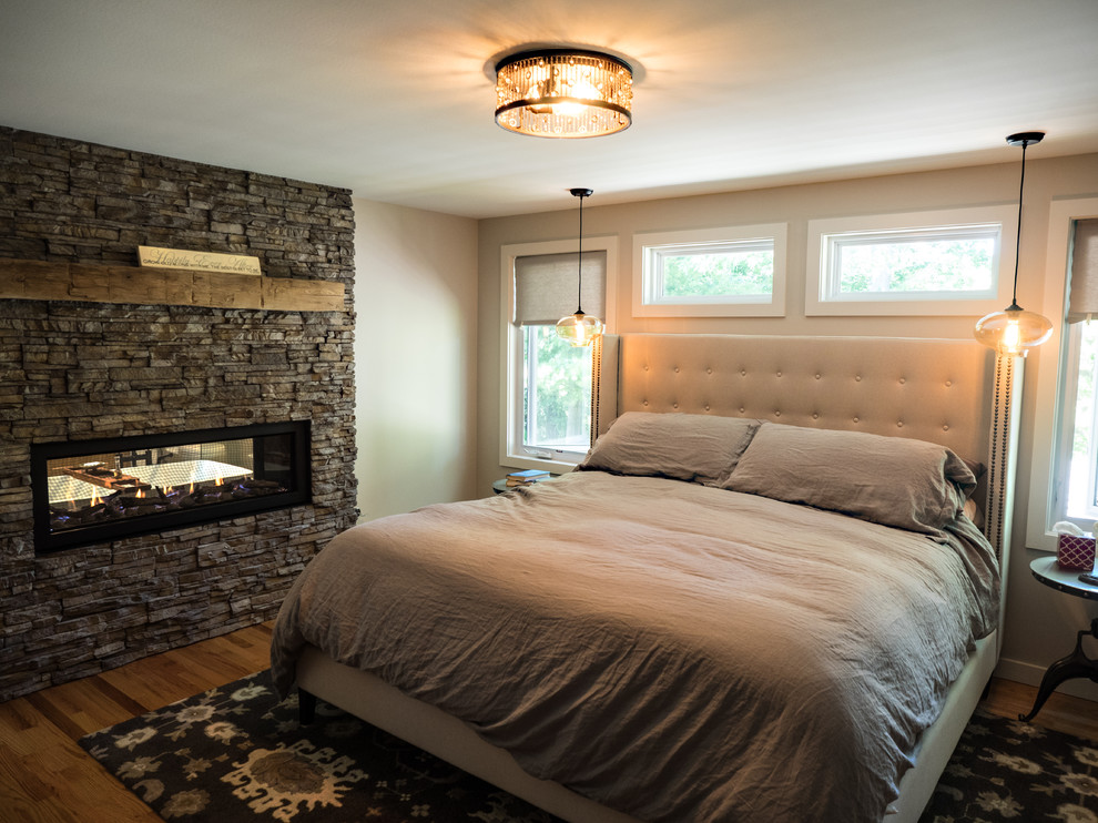 Источник вдохновения для домашнего уюта: хозяйская спальня среднего размера в стиле неоклассика (современная классика) с серыми стенами, паркетным полом среднего тона, двусторонним камином и фасадом камина из камня