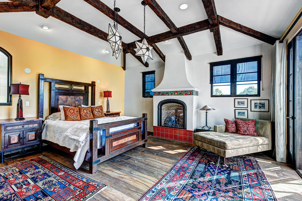 Large tuscan master medium tone wood floor bedroom photo in Santa Barbara with a standard fireplace, white walls and a plaster fireplace