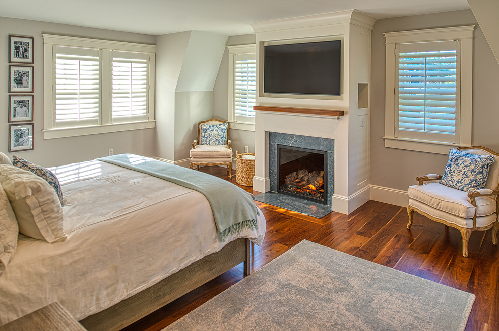 На фото: хозяйская спальня в классическом стиле с серыми стенами, темным паркетным полом, стандартным камином и коричневым полом с