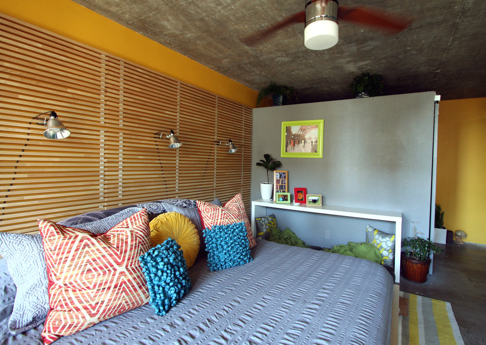 他の地域にある中くらいなコンテンポラリースタイルのおしゃれな主寝室 (黄色い壁、コンクリートの床、暖炉なし) のインテリア