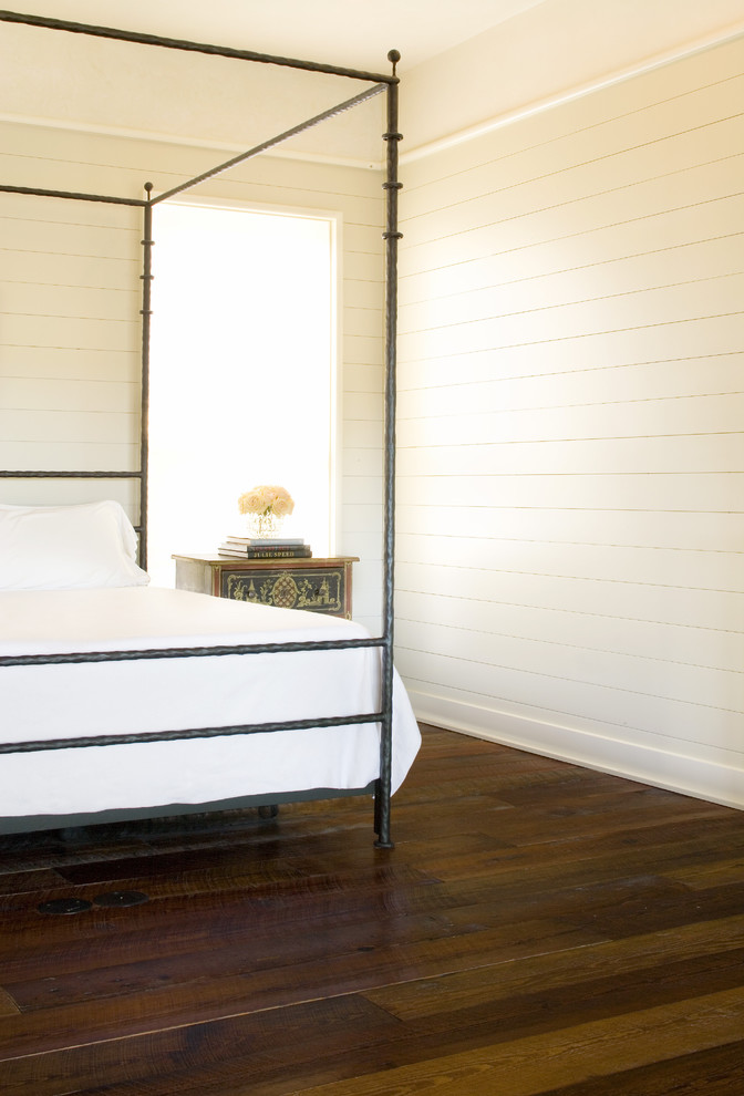 Uriges Schlafzimmer mit weißer Wandfarbe, dunklem Holzboden und braunem Boden in Austin