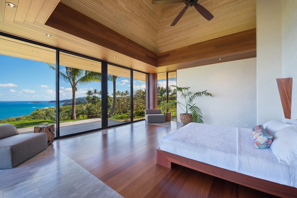 Imagen de dormitorio principal tropical grande sin chimenea con paredes beige, suelo de mármol y suelo beige