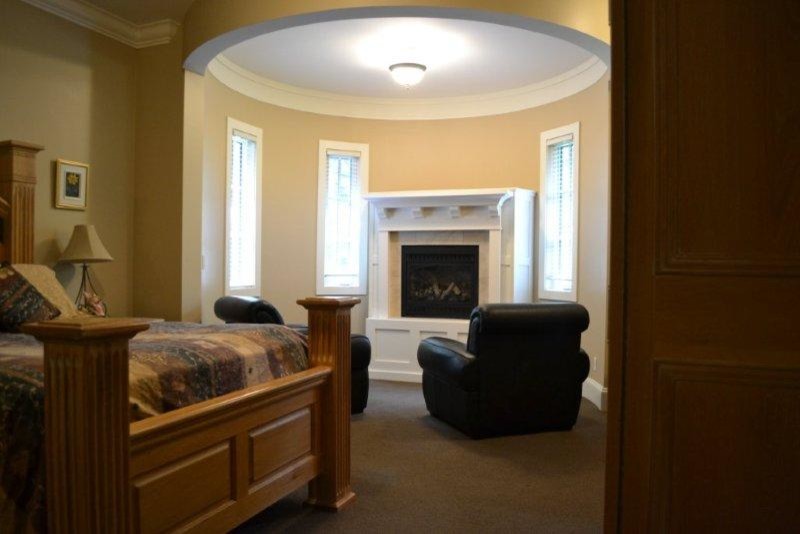Diseño de dormitorio principal retro grande con paredes beige, moqueta, chimenea de esquina y marco de chimenea de madera