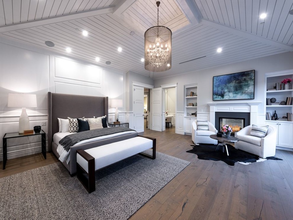Design ideas for a large traditional master bedroom in Los Angeles with white walls, medium hardwood flooring, a standard fireplace, a plastered fireplace surround and brown floors.