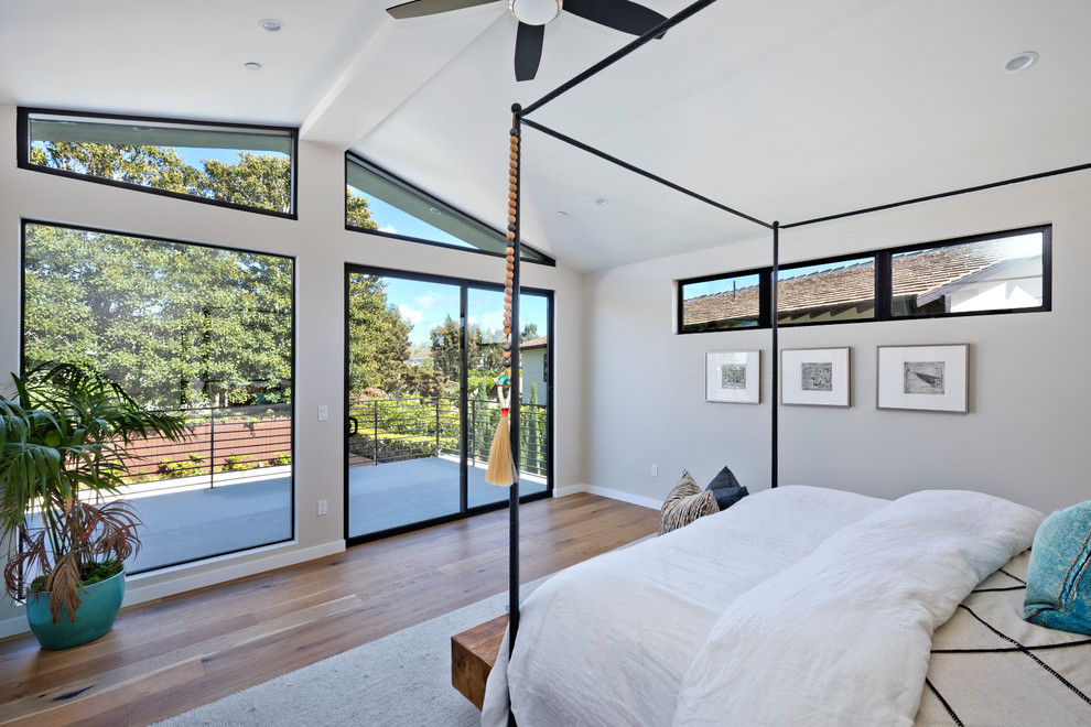 Diseño de dormitorio principal retro con paredes grises, suelo de madera en tonos medios y suelo marrón