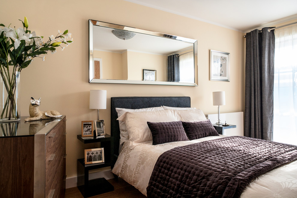 Ejemplo de dormitorio moderno de tamaño medio con paredes beige y suelo de madera clara