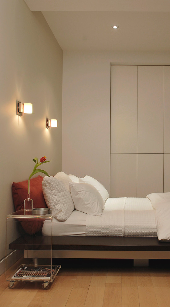 Modelo de dormitorio moderno con paredes beige y suelo de madera en tonos medios