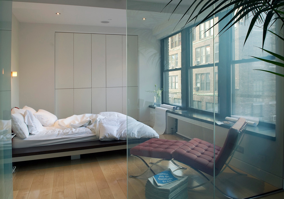 Inspiration pour une chambre minimaliste avec un mur blanc et un sol en bois brun.