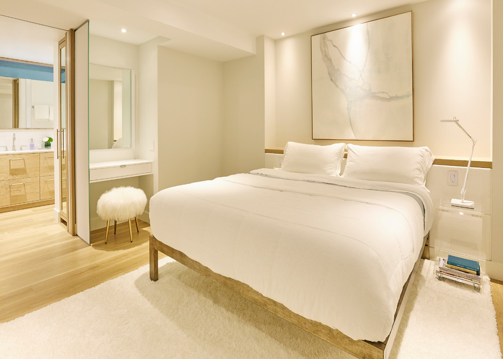 Modelo de dormitorio principal actual de tamaño medio con paredes blancas y suelo de madera clara