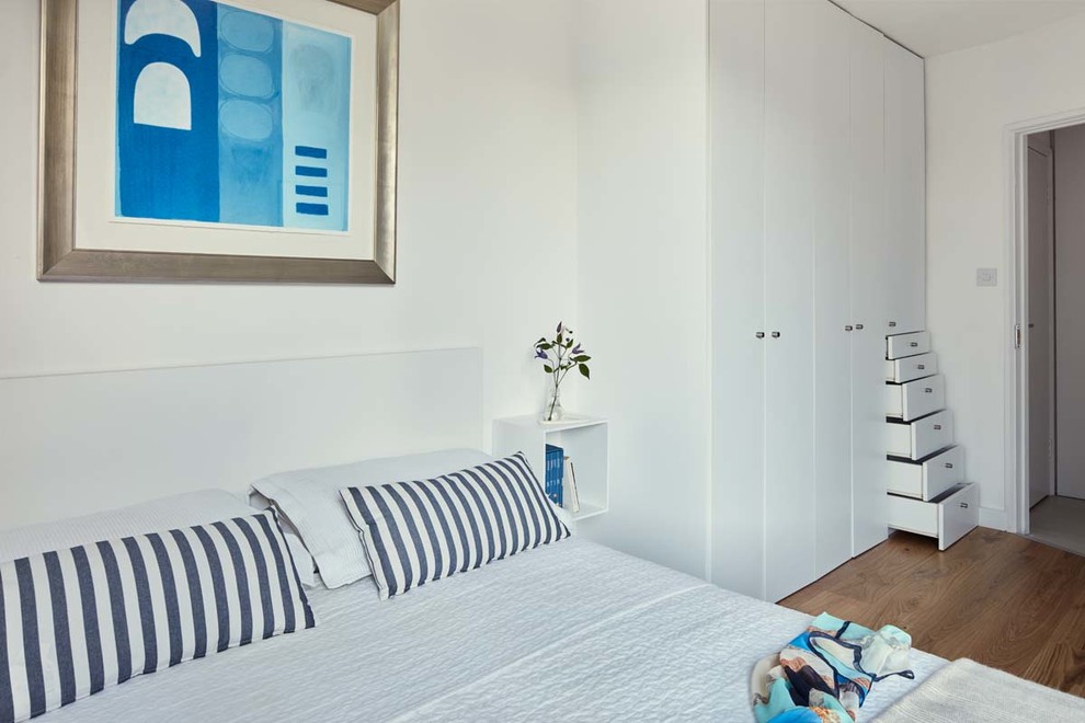 Diseño de dormitorio principal actual sin chimenea con paredes blancas y suelo de madera en tonos medios