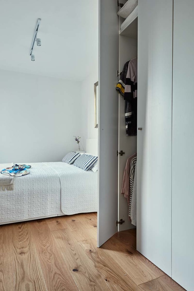 Foto di una camera matrimoniale minimal di medie dimensioni con pareti bianche, pavimento in legno massello medio e nessun camino